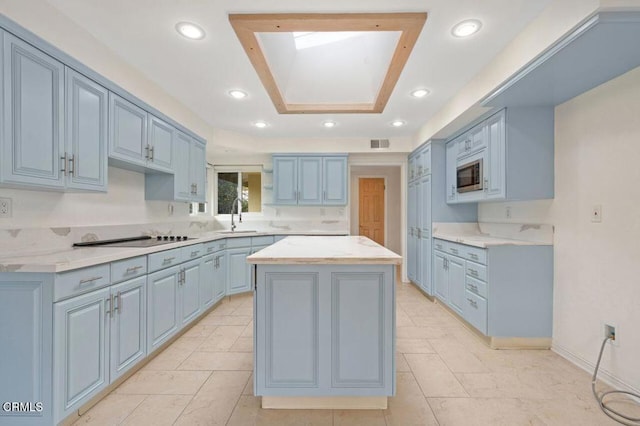 kitchen featuring sink, a center island, stainless steel microwave, and black electric cooktop