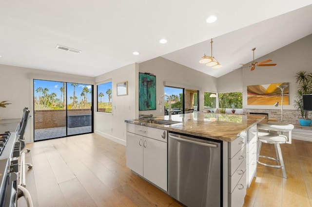 kitchen with sink, white cabinets, a center island, light stone counters, and stainless steel appliances