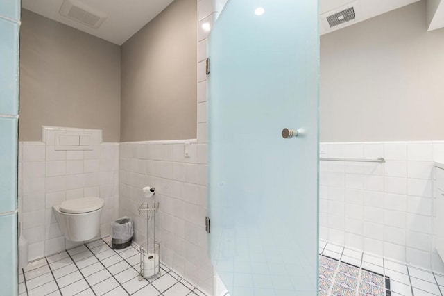 bathroom featuring tile patterned floors, toilet, and tile walls