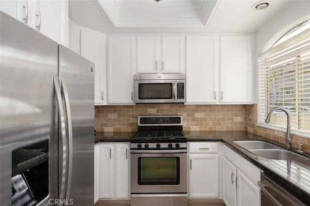 kitchen featuring sink, white cabinetry, dark stone countertops, stainless steel appliances, and tasteful backsplash