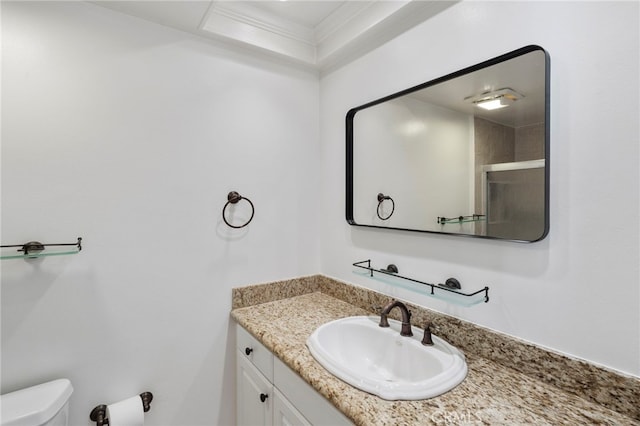 bathroom with vanity, crown molding, a shower with shower door, and toilet