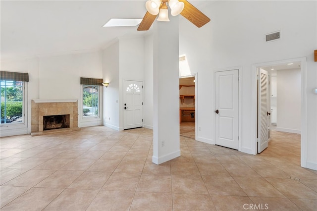 unfurnished living room featuring ceiling fan, a fireplace, high vaulted ceiling, and light tile patterned floors