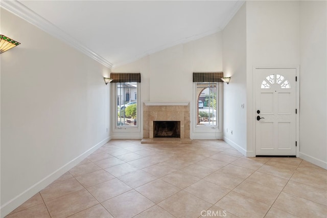 unfurnished living room featuring a tiled fireplace, crown molding, light tile patterned floors, and high vaulted ceiling