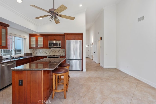 kitchen featuring a kitchen island, dark stone countertops, decorative backsplash, stainless steel appliances, and crown molding