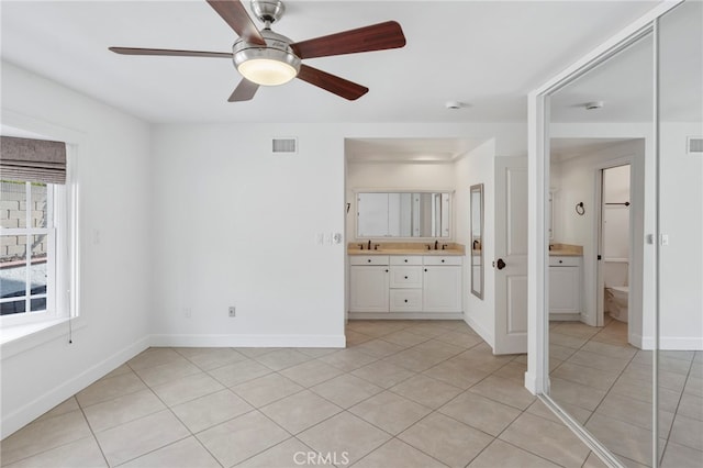 unfurnished bedroom with sink, ensuite bathroom, ceiling fan, and light tile patterned flooring