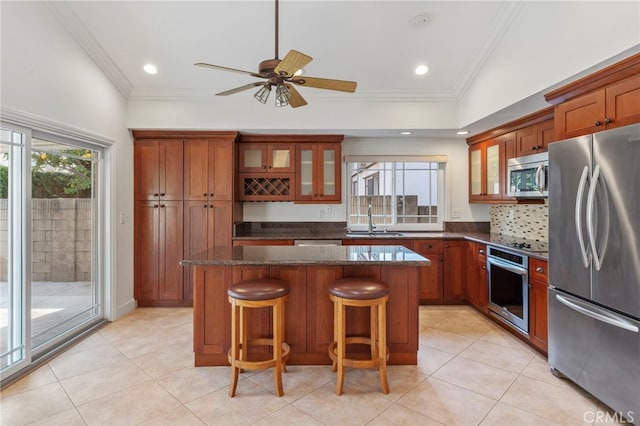 kitchen featuring appliances with stainless steel finishes, a breakfast bar, sink, dark stone countertops, and a center island