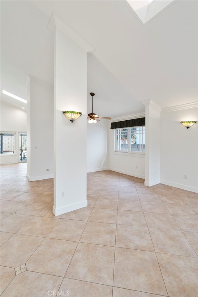 tiled empty room featuring crown molding, a skylight, high vaulted ceiling, and ceiling fan