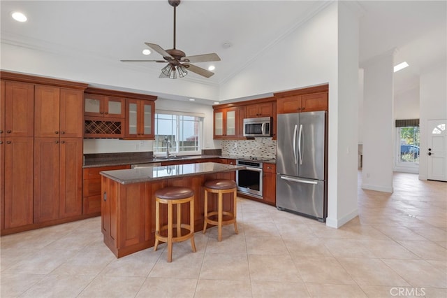 kitchen with ornamental molding, stainless steel appliances, a center island, and high vaulted ceiling