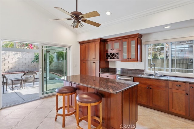 kitchen with crown molding, dark stone counters, a center island, and sink