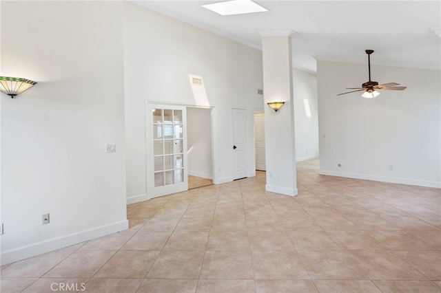 tiled spare room with ceiling fan, a skylight, and high vaulted ceiling