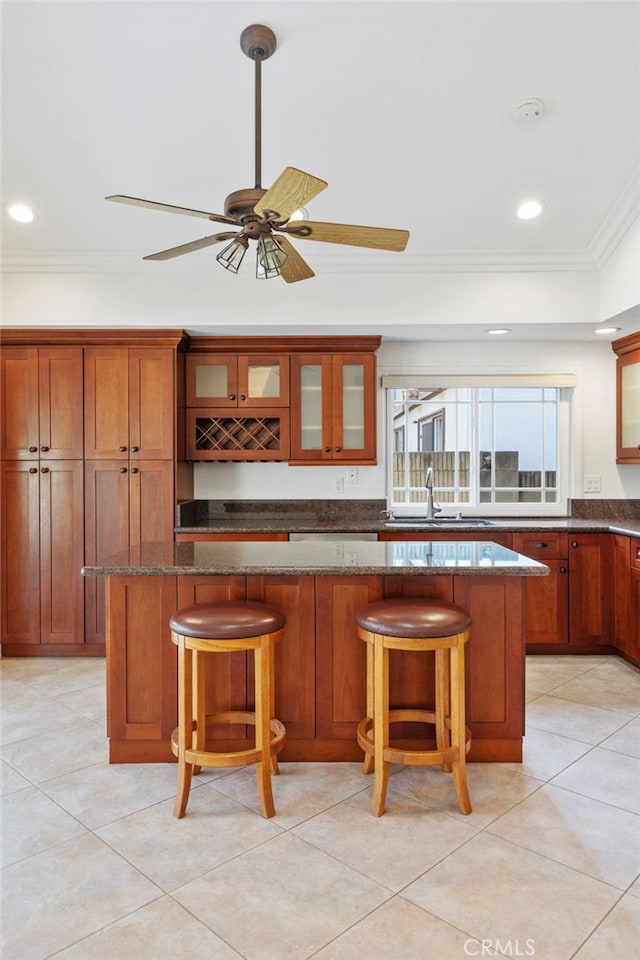 kitchen featuring ornamental molding, a kitchen island, dark stone countertops, and a kitchen bar