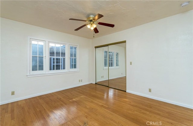 unfurnished bedroom with wood-type flooring, ceiling fan, and a closet