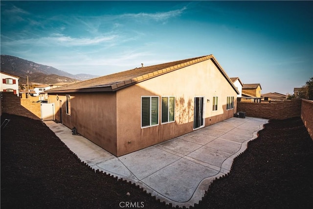 rear view of house featuring a mountain view, central AC, and a patio area