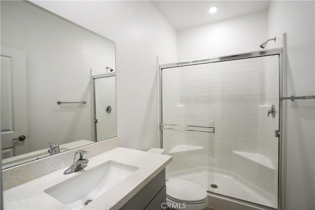 bathroom featuring vanity, a shower with shower door, and toilet