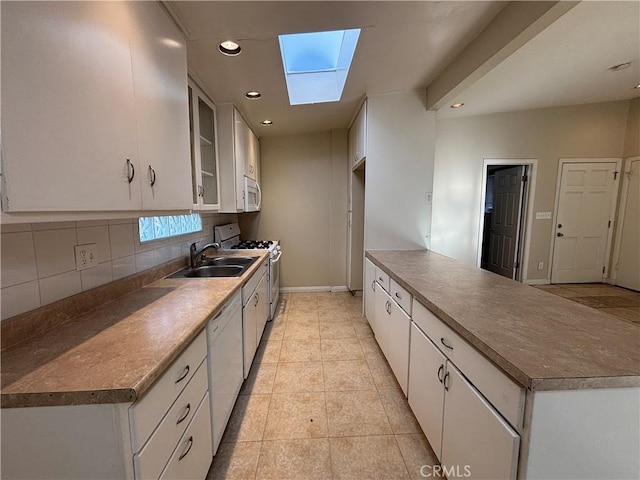 kitchen with sink, a skylight, white appliances, decorative backsplash, and white cabinets