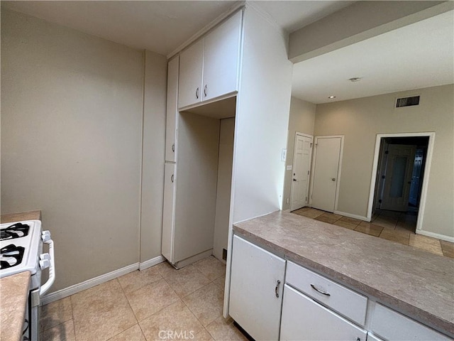 kitchen with white cabinetry, white range with gas stovetop, and light tile patterned floors