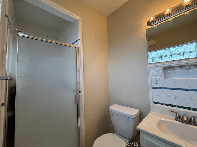 bathroom featuring vanity, a shower with shower door, and toilet