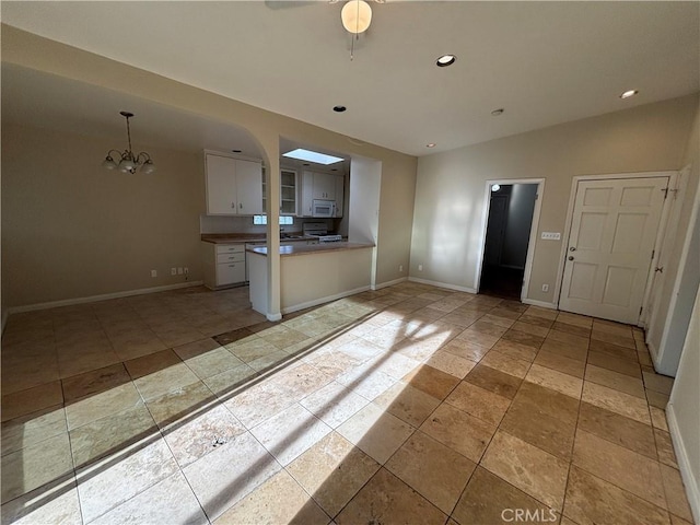 kitchen with white cabinetry, ceiling fan with notable chandelier, and pendant lighting