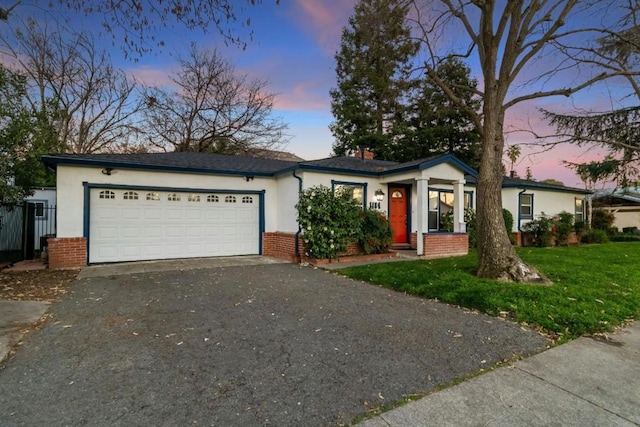 ranch-style home with a garage and a lawn