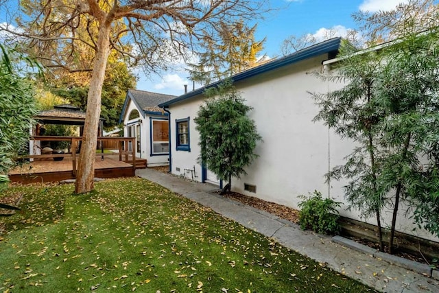 view of property exterior with a wooden deck and a yard