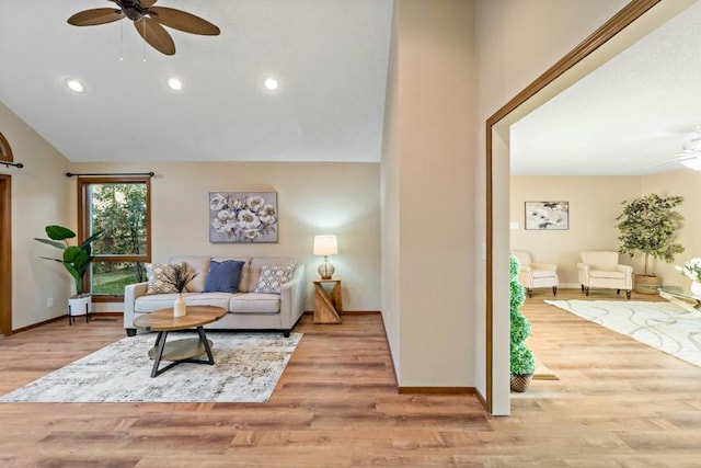 living room with light hardwood / wood-style flooring, ceiling fan, and vaulted ceiling