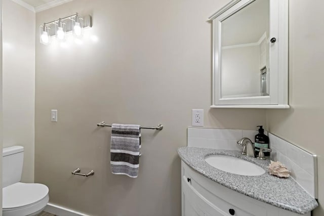 bathroom with vanity, backsplash, crown molding, and toilet