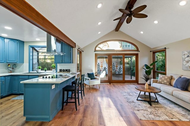 living room featuring light hardwood / wood-style flooring, sink, a wealth of natural light, and beamed ceiling