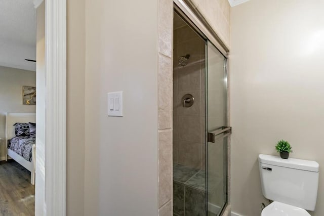 bathroom with hardwood / wood-style floors, an enclosed shower, and toilet