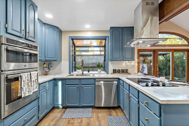 kitchen featuring blue cabinetry, sink, tasteful backsplash, island exhaust hood, and stainless steel appliances