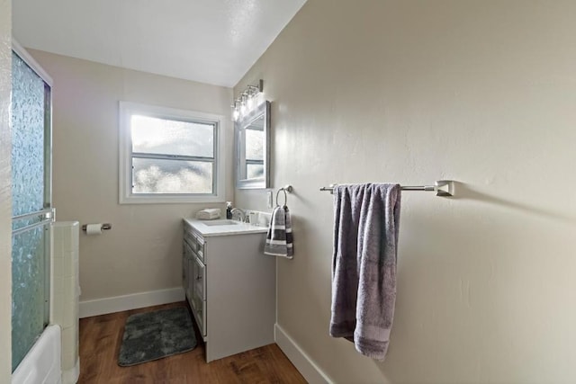 bathroom with vanity, hardwood / wood-style floors, and washtub / shower combination