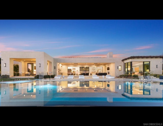 pool at dusk featuring a patio area