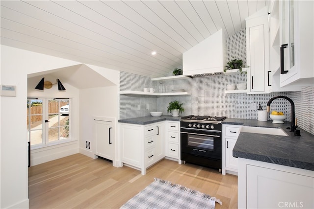 kitchen with white cabinetry, lofted ceiling, sink, high end stove, and custom exhaust hood