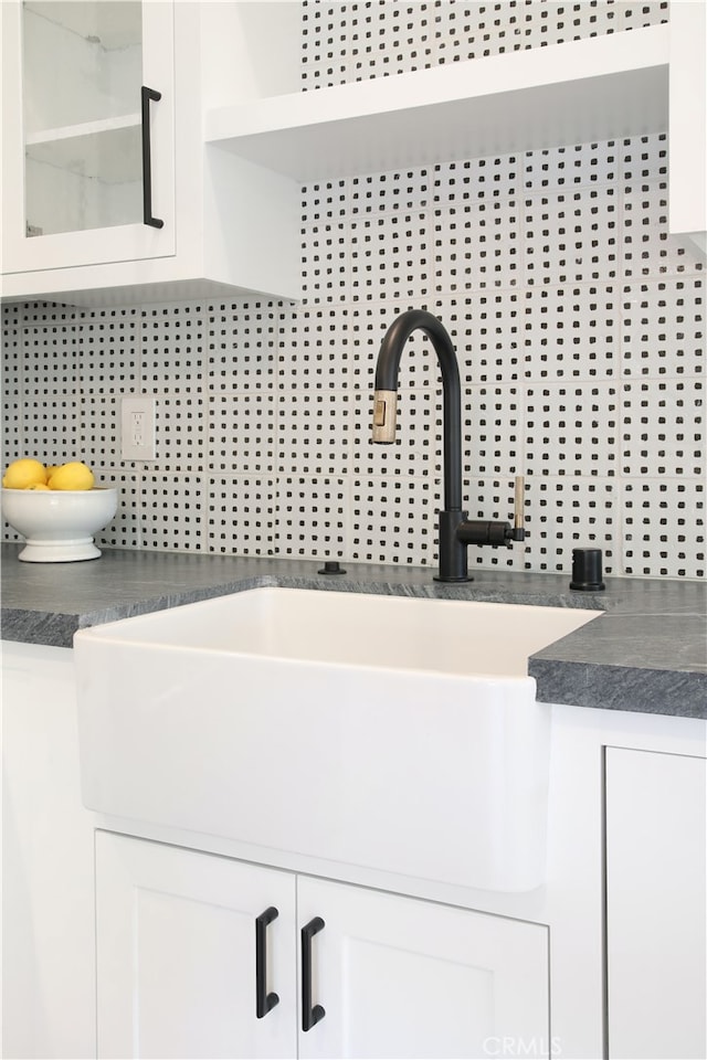 details featuring sink, white cabinets, and decorative backsplash