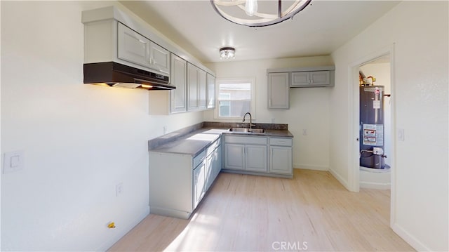 kitchen with gas water heater, sink, gray cabinetry, and light hardwood / wood-style flooring