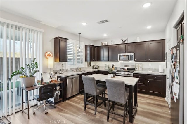 kitchen with dark brown cabinetry, sink, decorative light fixtures, light wood-type flooring, and stainless steel appliances