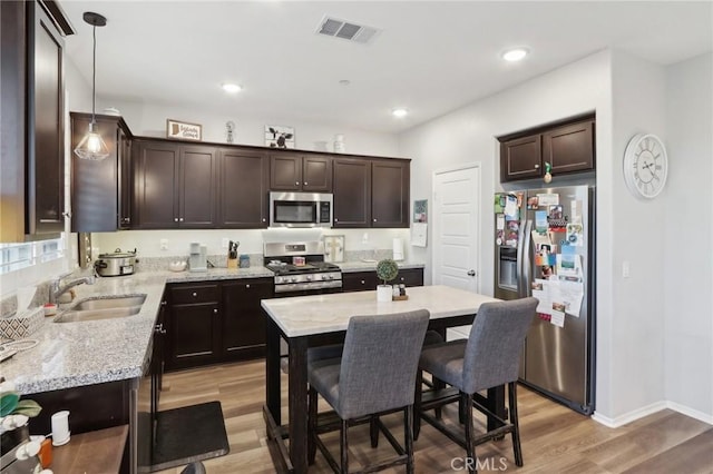 kitchen featuring a kitchen island, pendant lighting, sink, dark brown cabinetry, and stainless steel appliances