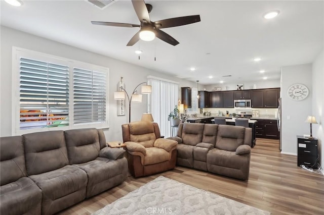 living room with light hardwood / wood-style flooring and ceiling fan