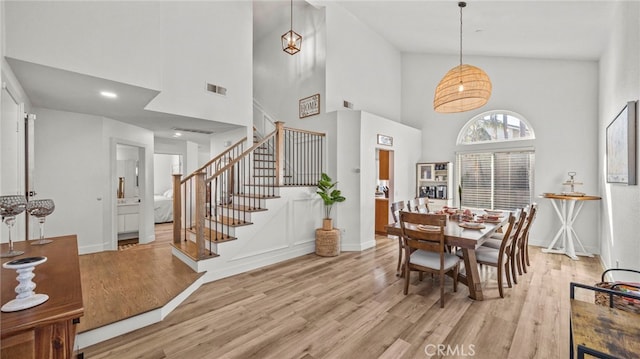 dining area featuring stairs, light wood-style flooring, visible vents, and baseboards