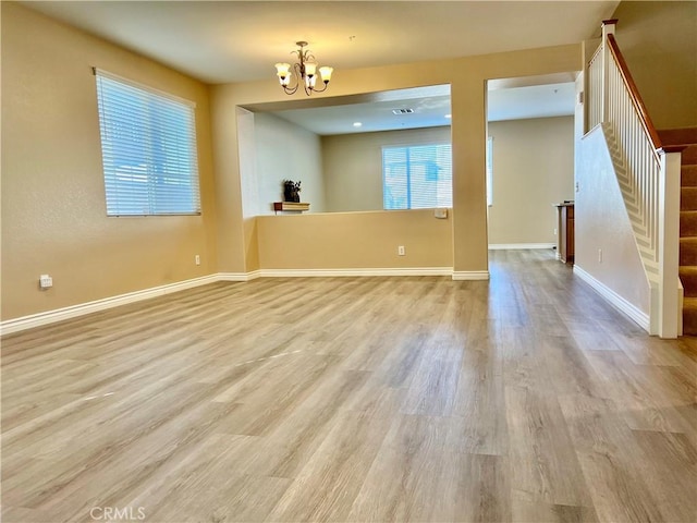 unfurnished room featuring a notable chandelier and light wood-type flooring