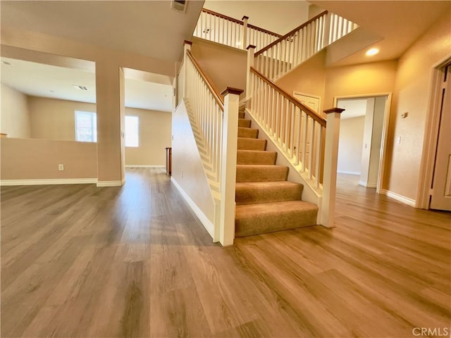 staircase featuring a high ceiling and wood-type flooring