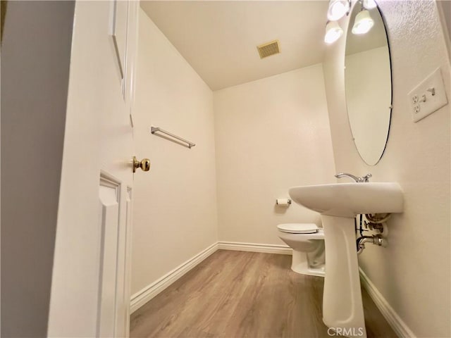 bathroom featuring wood-type flooring and toilet