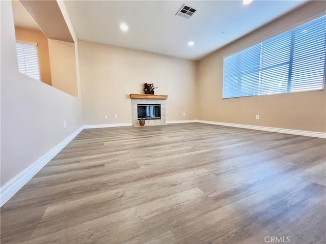 unfurnished living room with a tiled fireplace and hardwood / wood-style floors