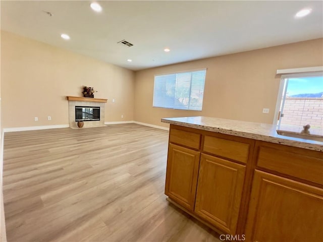 unfurnished living room featuring a tiled fireplace, sink, and light wood-type flooring