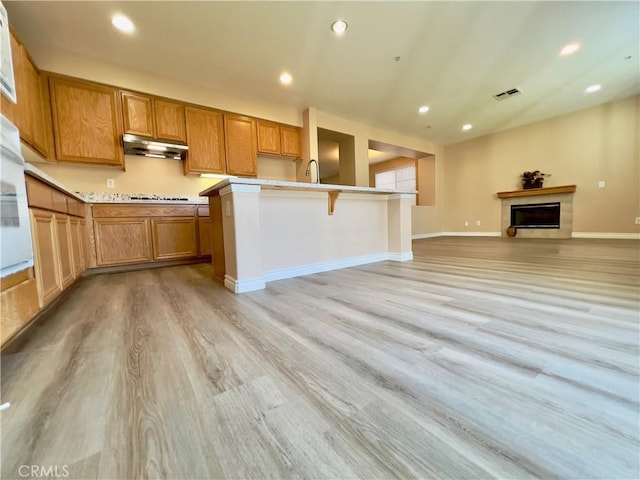 kitchen featuring sink, stovetop, a breakfast bar area, and light hardwood / wood-style floors