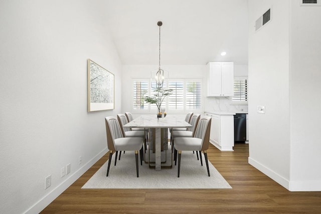 dining area featuring an inviting chandelier, dark wood-type flooring, and lofted ceiling