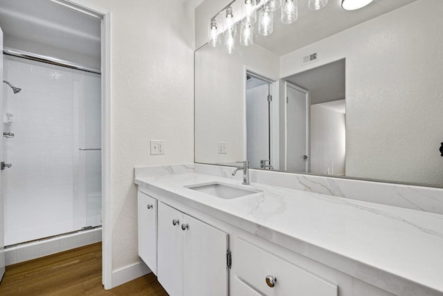 bathroom with hardwood / wood-style flooring, vanity, and a shower with shower door