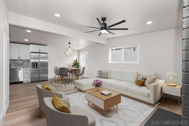 living room featuring ceiling fan, vaulted ceiling with beams, and light wood-type flooring