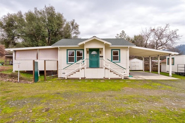 view of front of property featuring a carport, a front lawn, and a storage shed