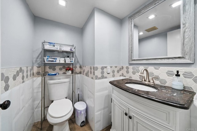 bathroom with tile walls, vanity, and toilet