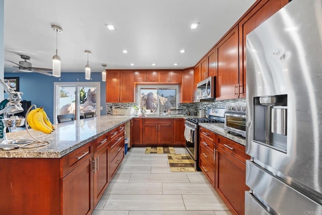 kitchen featuring decorative light fixtures, kitchen peninsula, stainless steel appliances, light stone countertops, and decorative backsplash